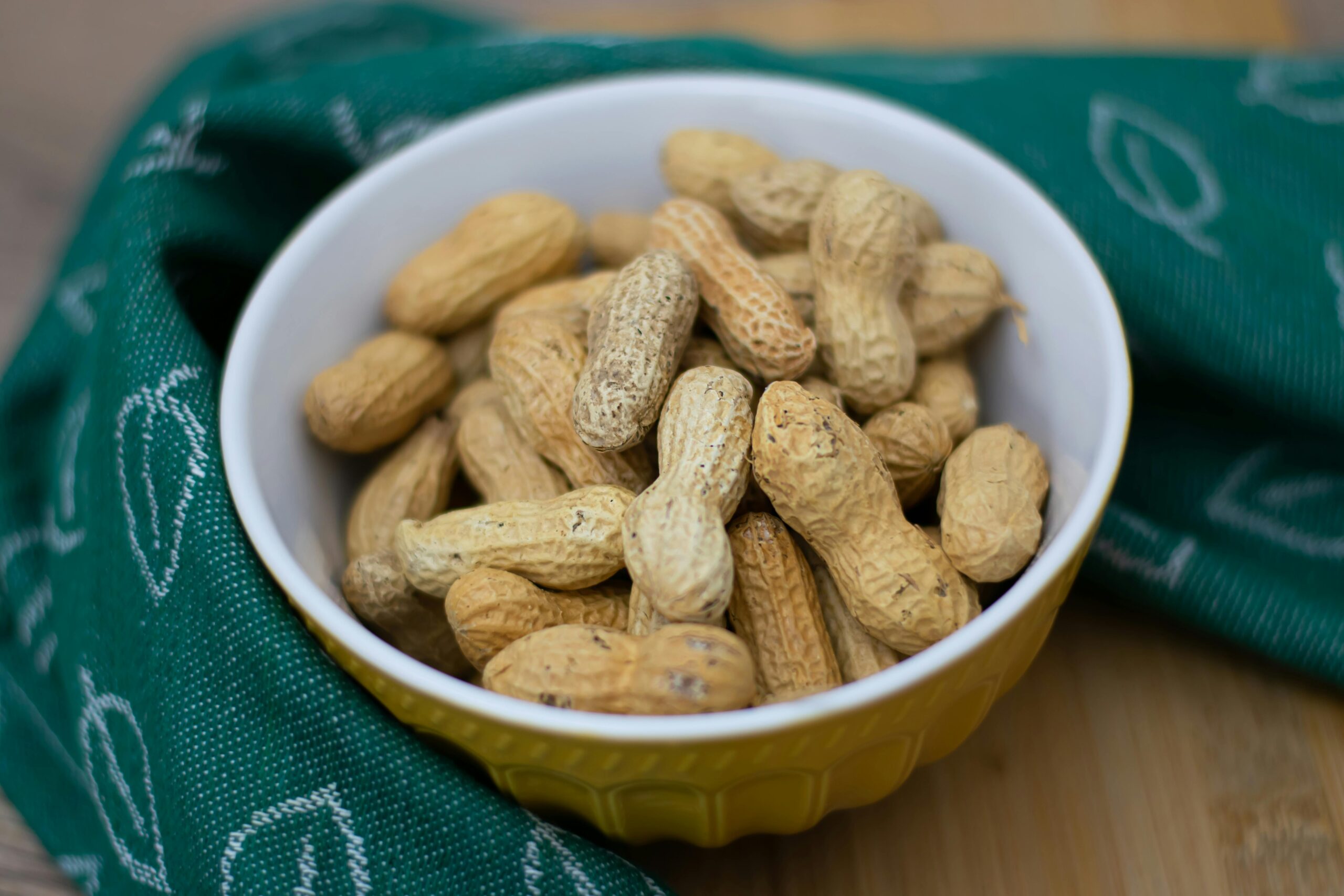 A close-up of unshelled peanuts in a yellow bowl, perfect for food-related concepts.